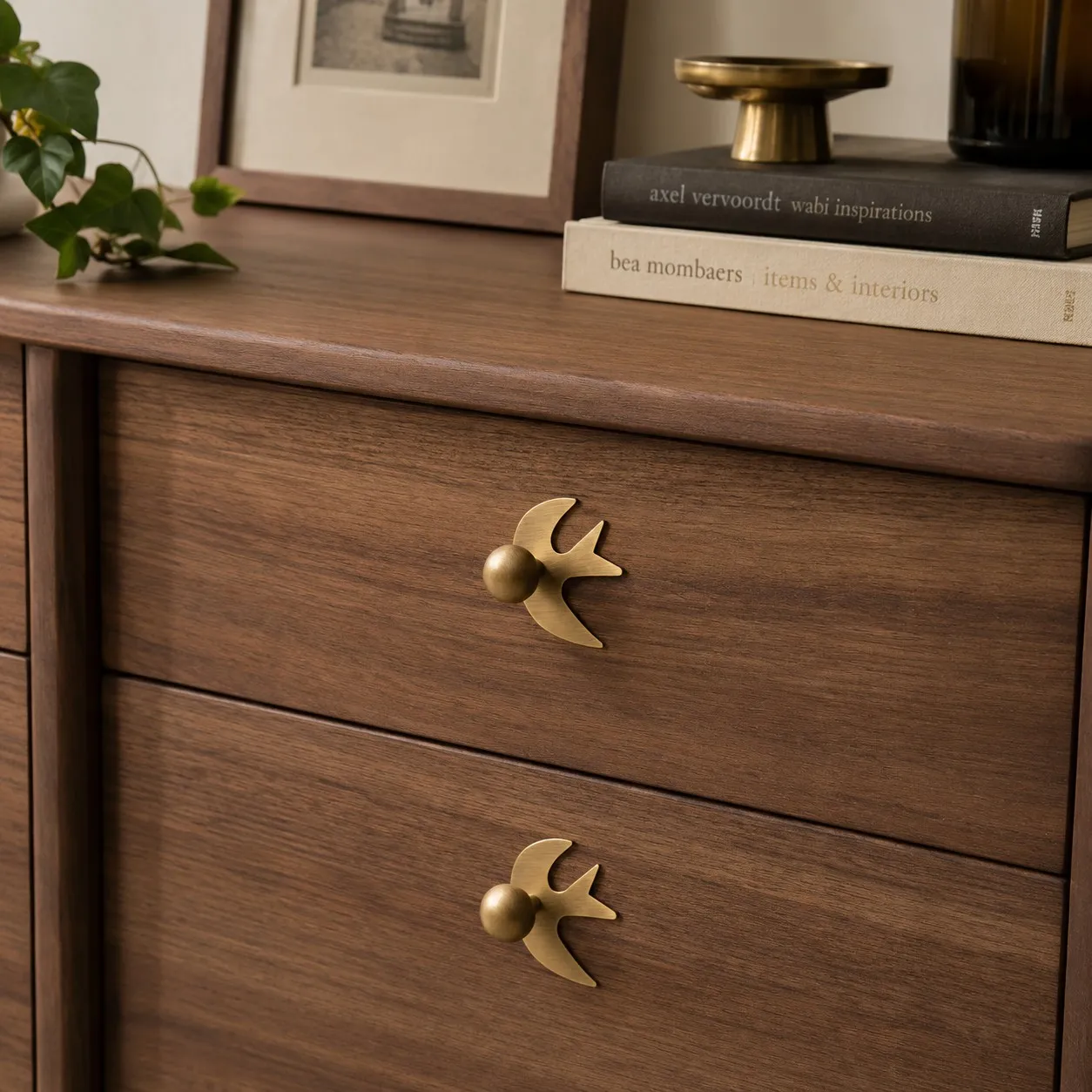 Swallow-shaped brass handles on wood drawers
